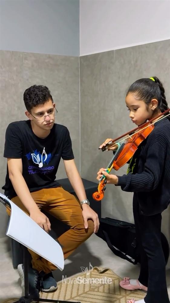 Professor acompanhando aluna na aula de violino